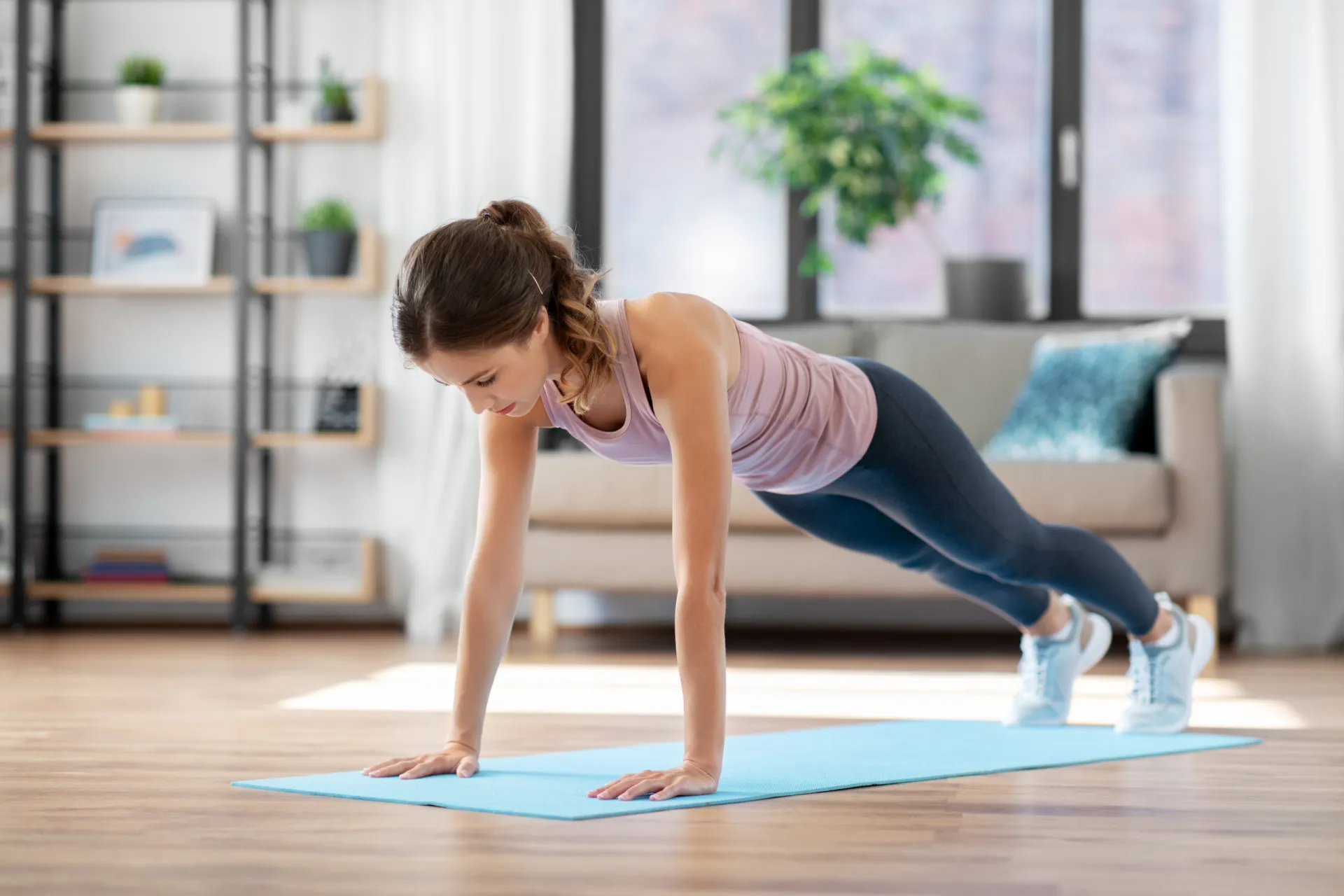 42867844 young woman doing plank exercise on mat at home