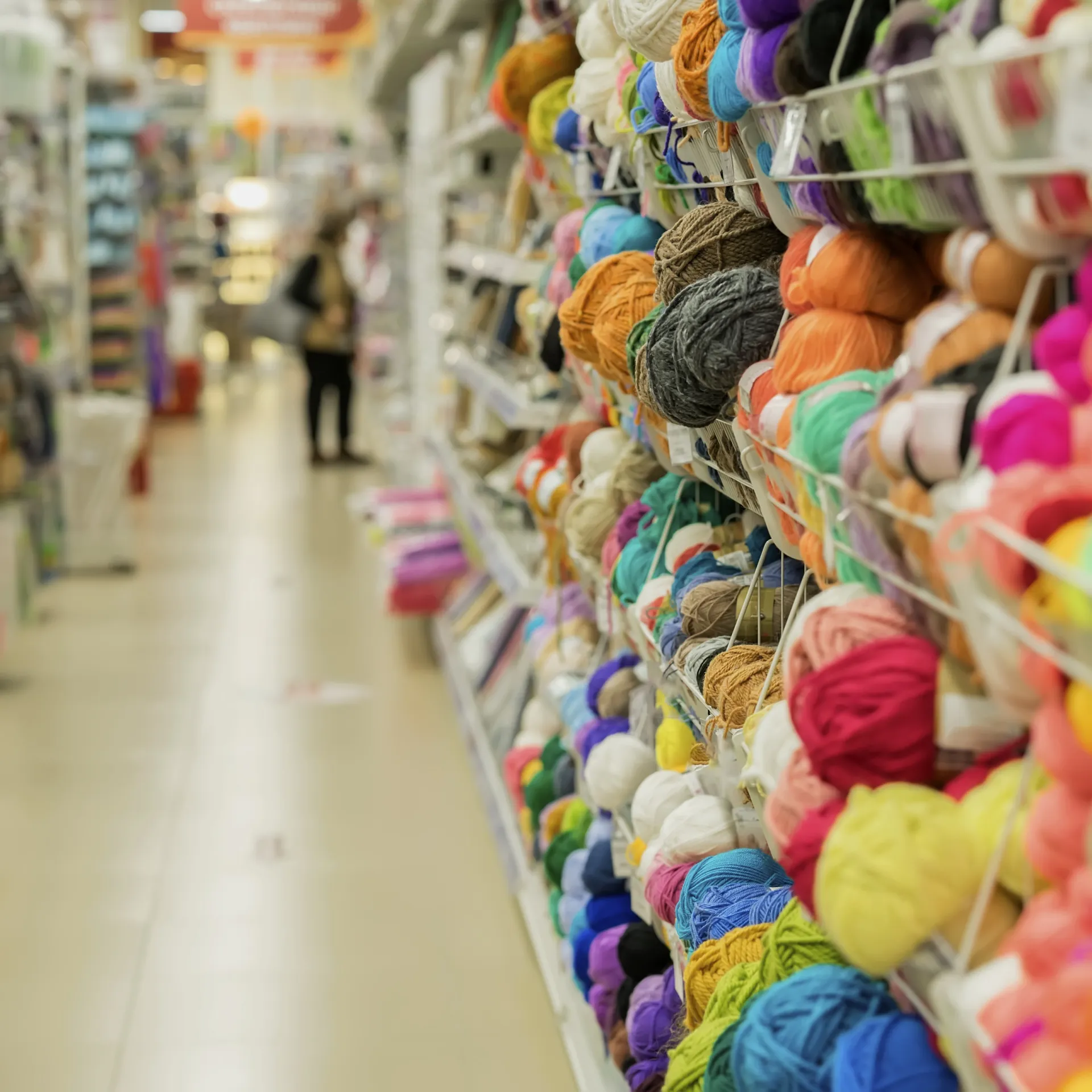 mp26369720 woman makes choosing yarn for knitting in the store of goods for creativity and needlework shelves in needlework store hobby needlework defocused motion blurred
